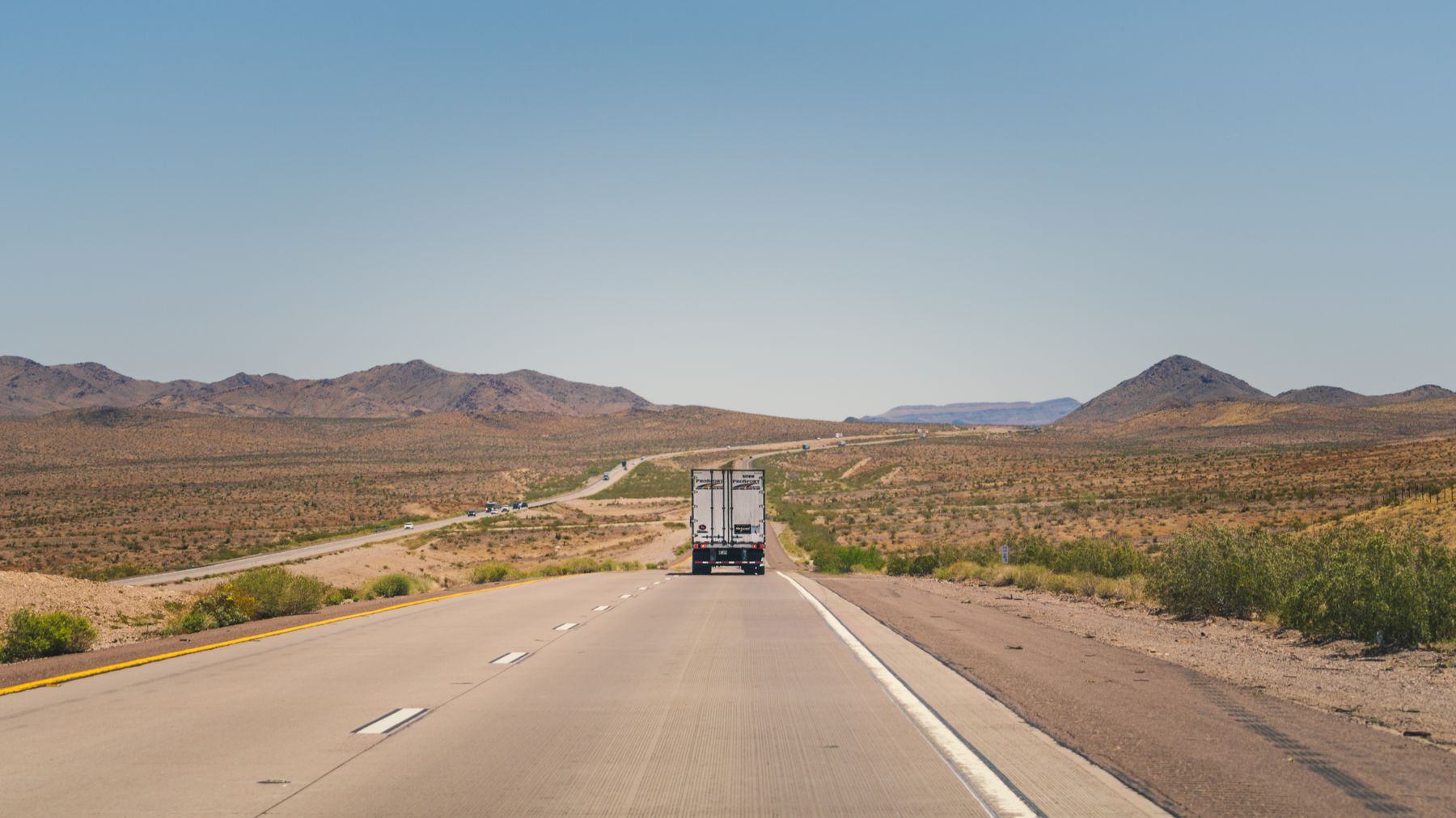Freight truck traveling on an Arizona desert highway under a clear blue sky
